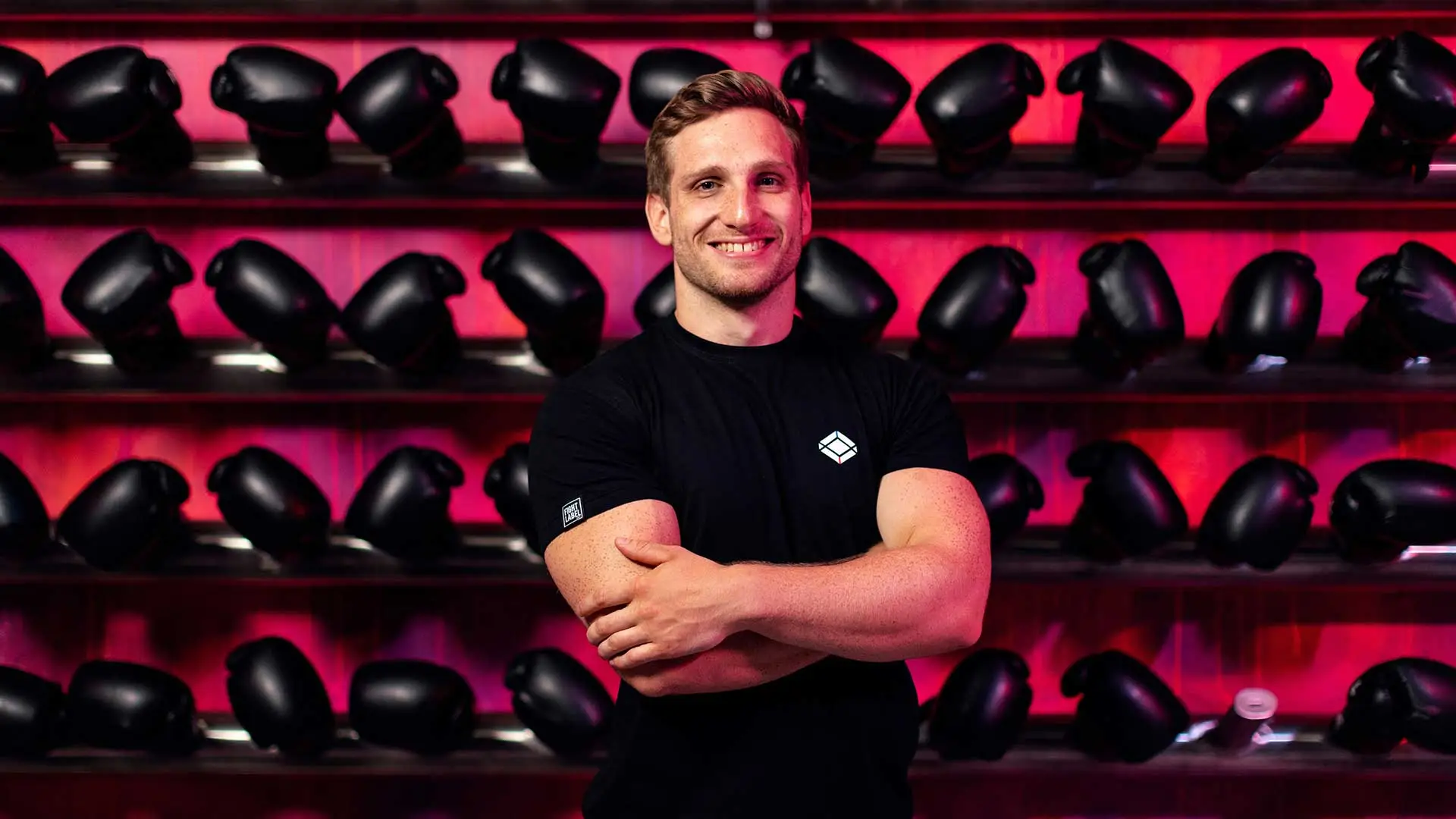 A trainer in front of a wall of boxing gloves needs insurance coverage for personal trainers